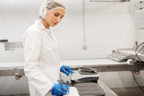 food production, industry and people concept - woman weighing ic